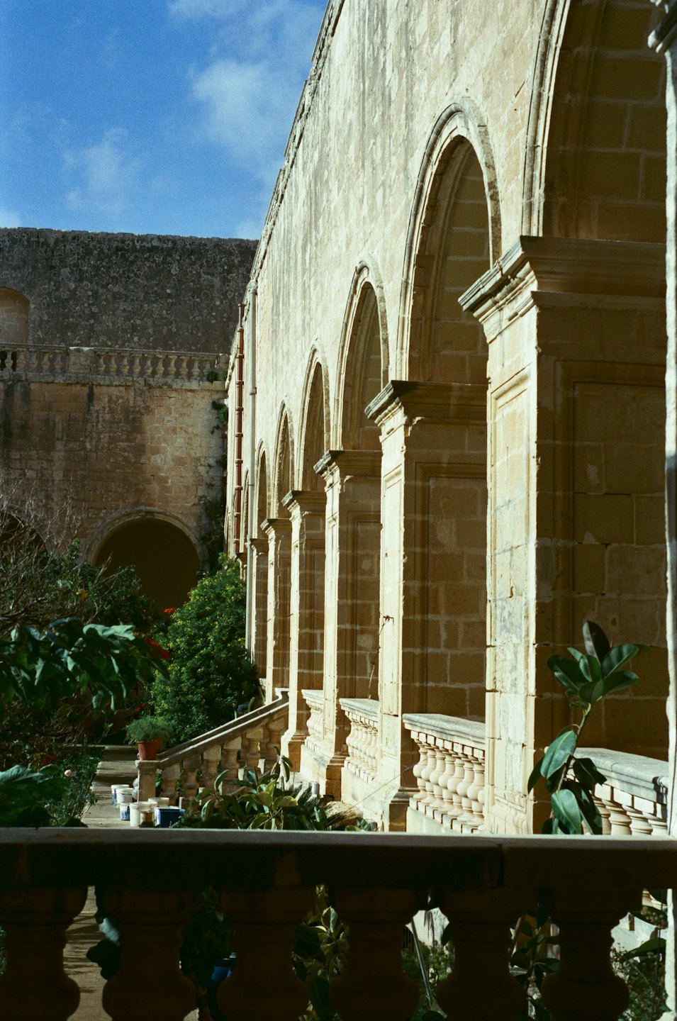 Archi e colonne di pietra circondano un cortile verde.